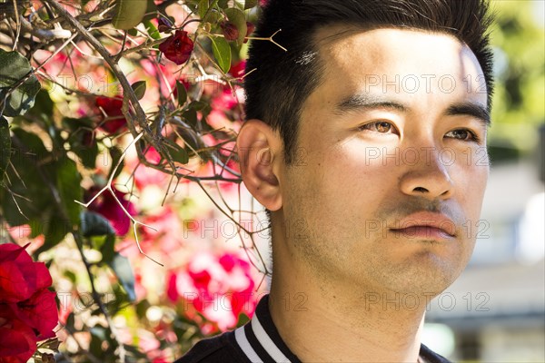 Portrait of serious Chinese man near flowering tree