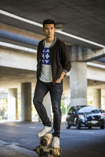 Serious Chinese man standing on hydrant