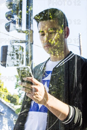 Serious Chinese man texting on cell phone behind window