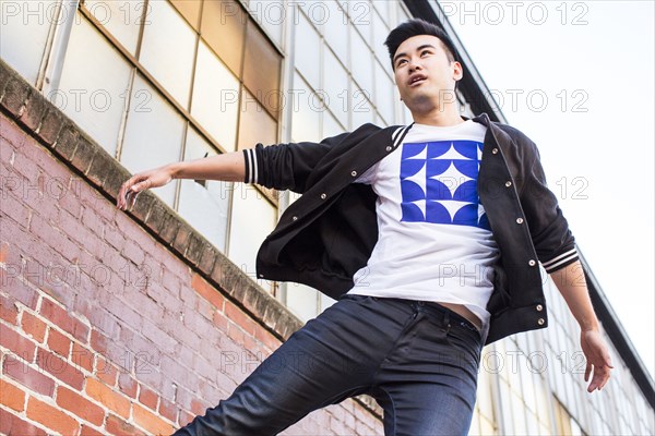 Chinese man jumping near red brick wall