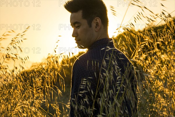 Smiling Chinese man standing in field of wheat