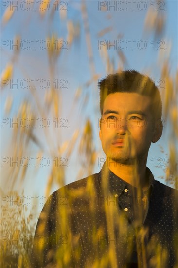 Serious Chinese man standing in wheat