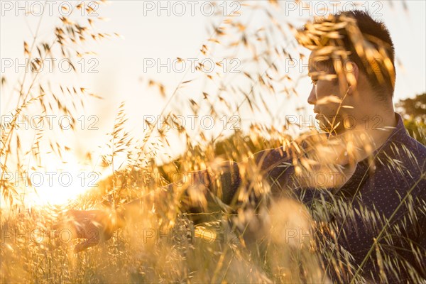 Serious Chinese man sitting in field of wheat