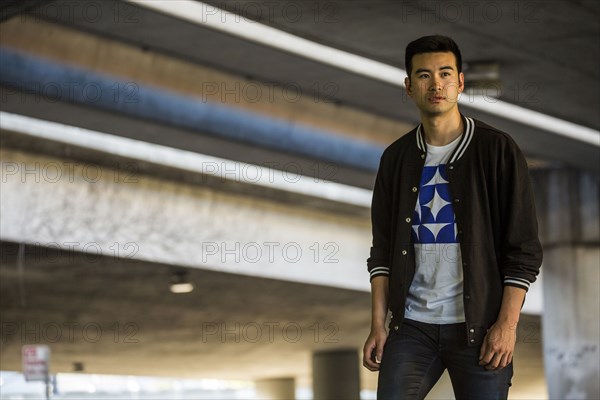 Chinese man standing under urban overpass