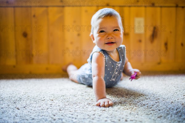 Smiling mixed race baby girl crawling on carpet