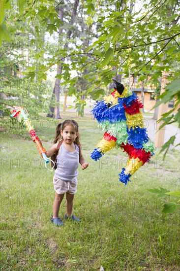 Mixed race girl hitting pinata outdoors