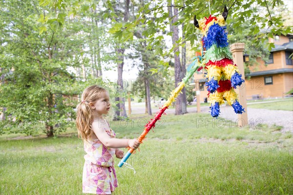 Caucasian girl hitting pinata outdoors