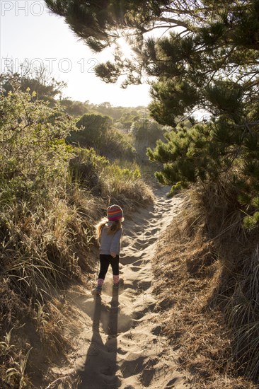 Caucasian girl walking on sandy path