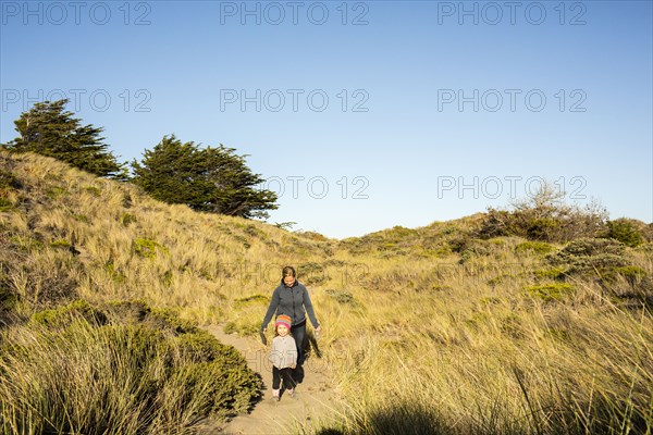 Caucasian mother and daughter walking on sandy path