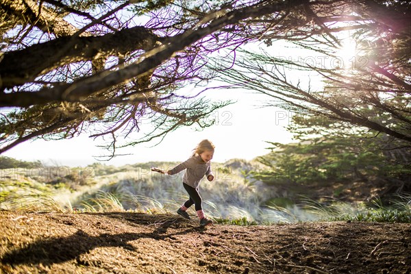 Caucasian girl running under tree branches