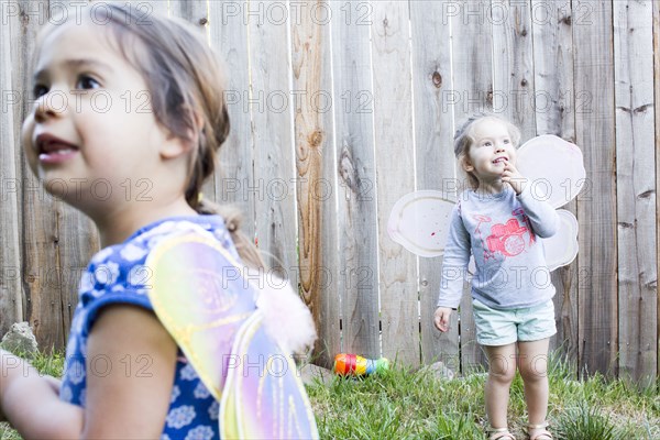 Curious girls wearing fairy wings in backyard