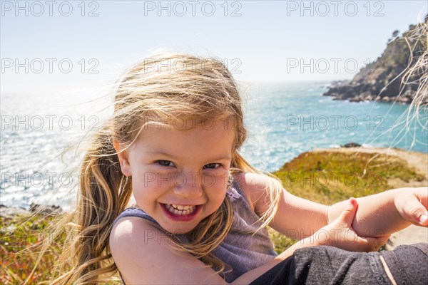 Wind blowing hair of smiling Caucasian girl near ocean