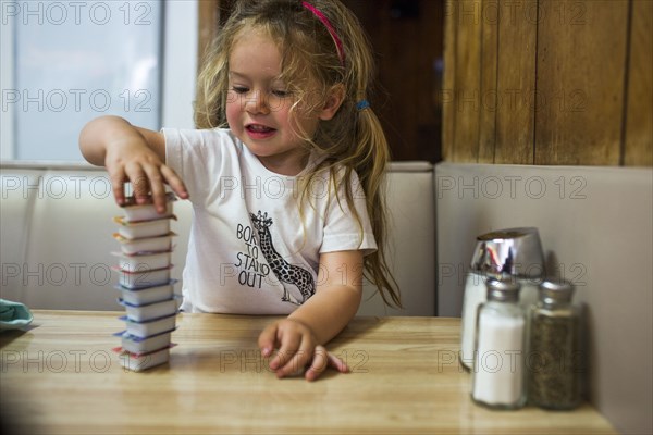 Smiling Caucasian girl stacking jelly containers in restaurant booth