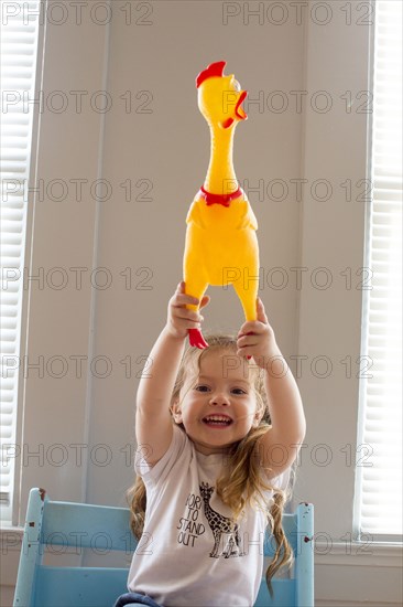 Smiling Caucasian girl holding rubber chicken