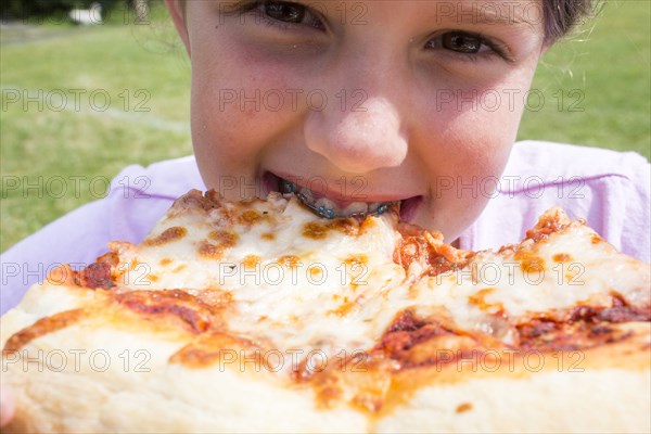 Close up of Caucasian girl with braces biting pizza