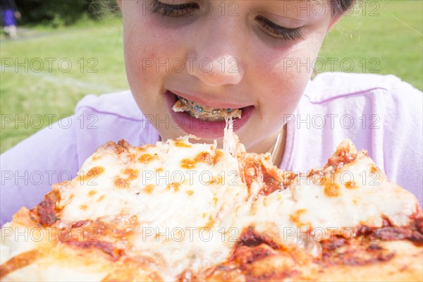 Close up of Caucasian girl with braces biting pizza