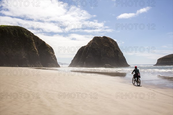 Distant Caucasian woman riding bicycle on beach