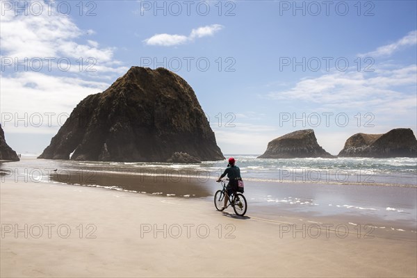 Caucasian woman riding bicycle on beach