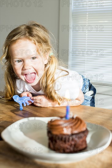 Happy Caucasian girl near birthday cupcake