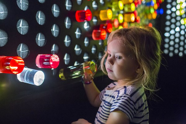 Caucasian girl placing colorful game pieces on puzzle wall