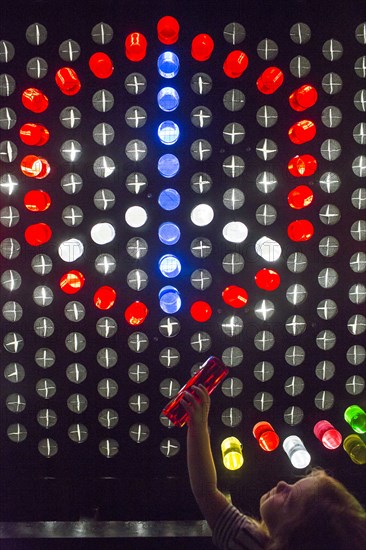 Caucasian girl placing colorful game pieces on puzzle wall