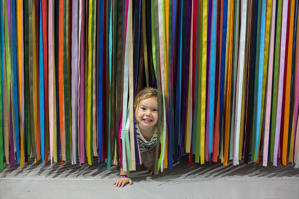 Caucasian girl crawling under colorful hanging streamers