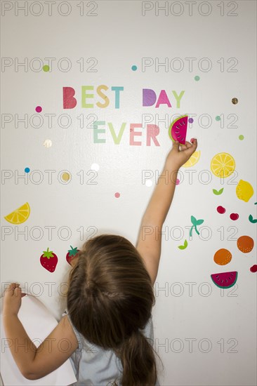 Caucasian girl placing watermelon decoration on wall