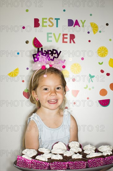 Caucasian girl carrying tray of cupcakes for birthday