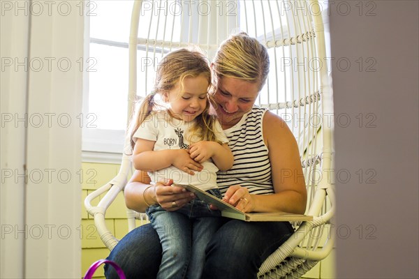 Caucasian mother reading book to daughter on lap