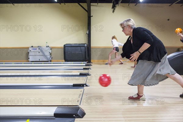 Caucasian woman releasing bowling ball in lane