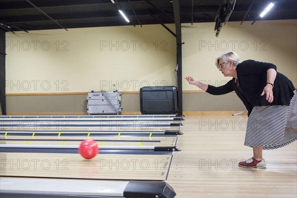 Caucasian woman releasing bowling ball in lane