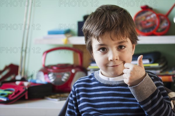 Caucasian boy giving thumbs up at desk