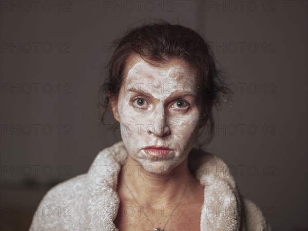 Caucasian woman wearing face cream and bathrobe