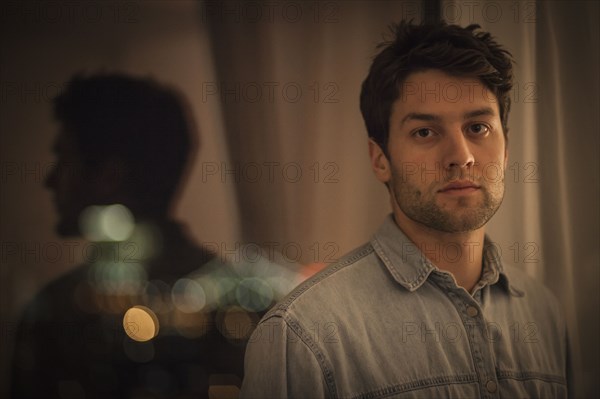 Caucasian man standing near window at night