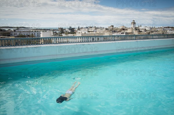 Caucasian woman swimming in urban rooftop pool