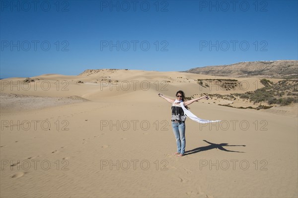 Caucasian woman cheering on sand dune