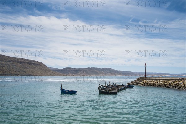Boats docked on rocky pier in remote harbor