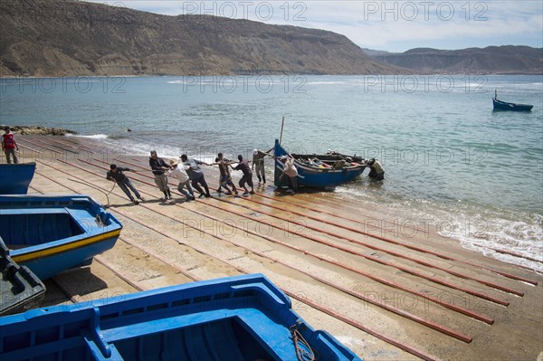 People pulling boat onto boat ramp