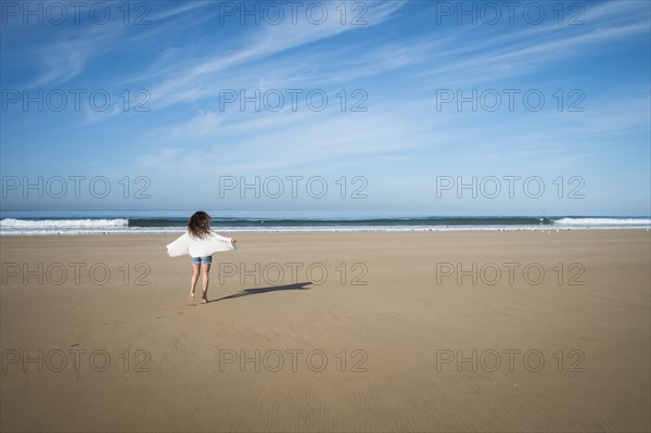 Caucasian woman walking on beach under blue sky