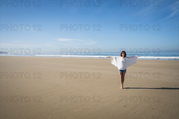 Caucasian woman walking on beach under blue sky