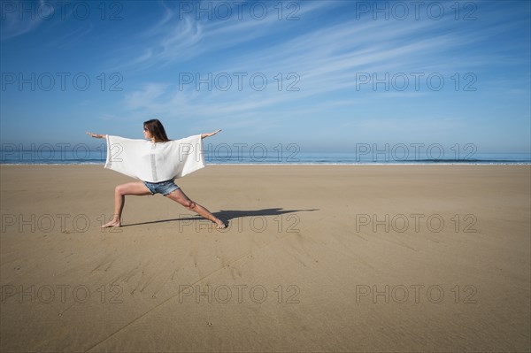 Caucasian woman practicing yoga on beach