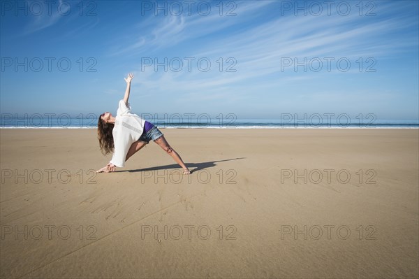 Caucasian woman practicing yoga on beach