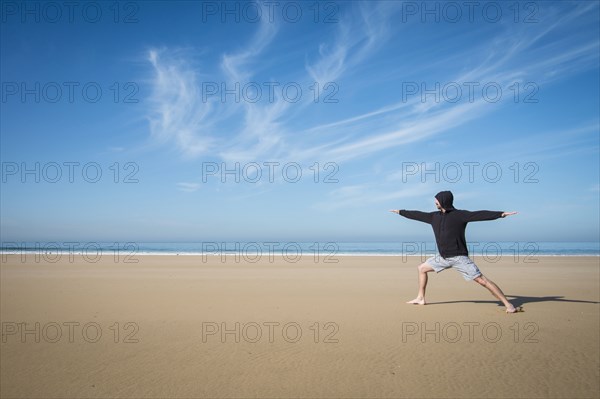 Caucasian man practicing yoga on beach