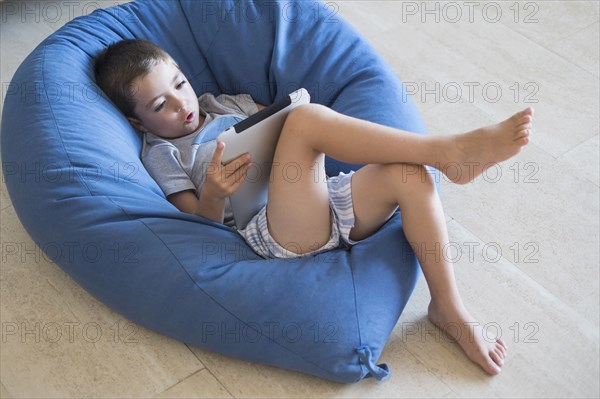 Caucasian boy using digital tablet in beanbag chair