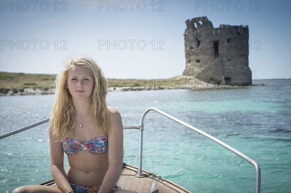 Smiling girl sunbathing on sailboat near ancient ruins