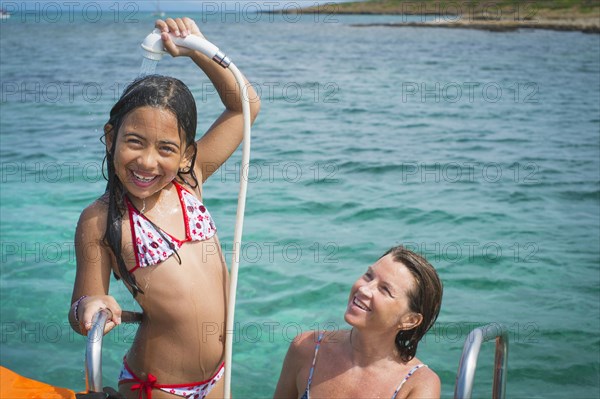 Mother and daughter playing on boat in water