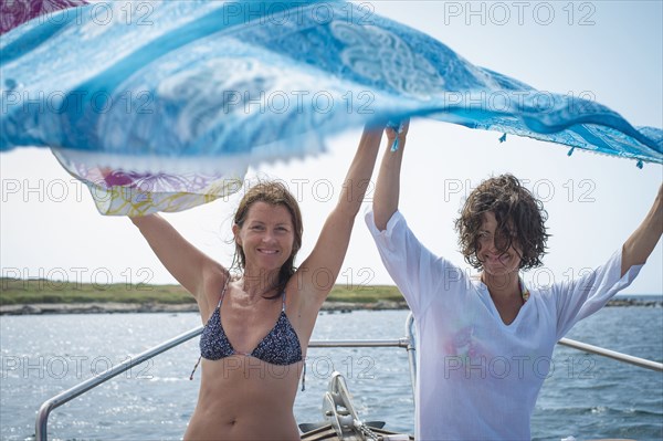Women spreading blanket on boat in water