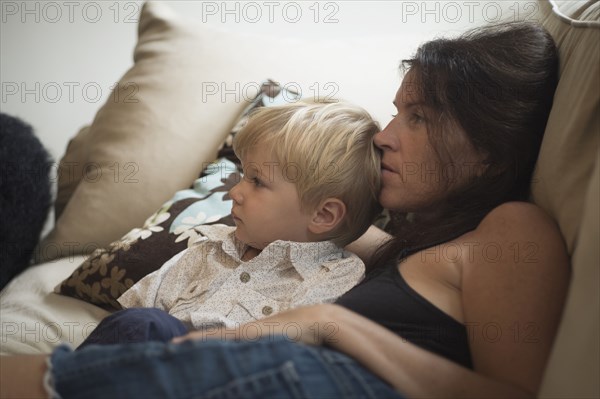 Caucasian mother and son watching television