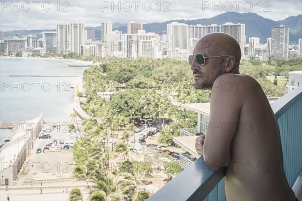 Caucasian man admiring urban ocean view from balcony