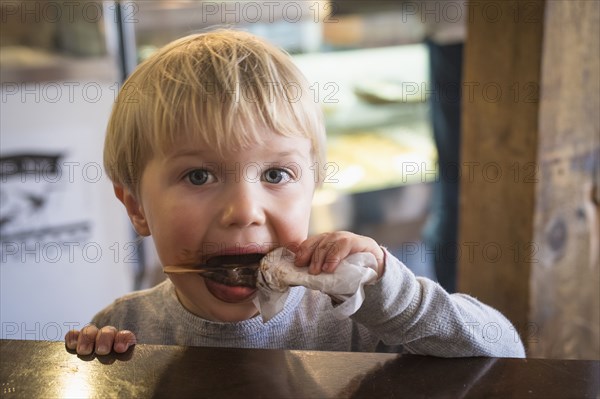 Messy Caucasian boy eating popsicle in kitchen